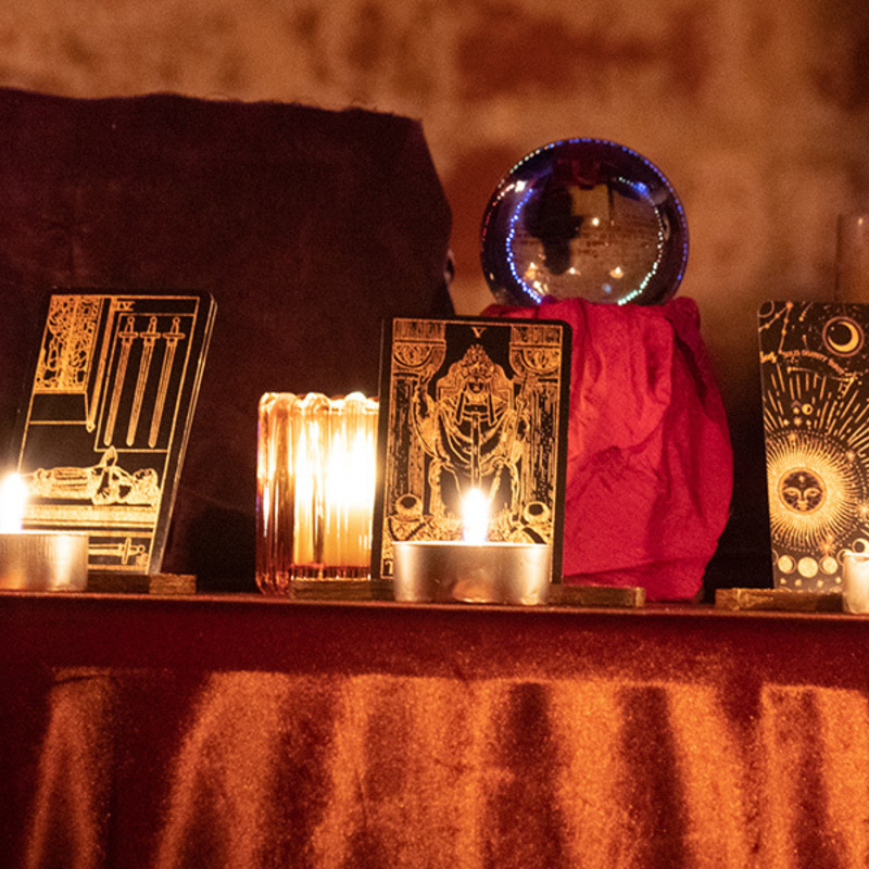 Tarot cards adorn the Storyteller's table, lit by candles.