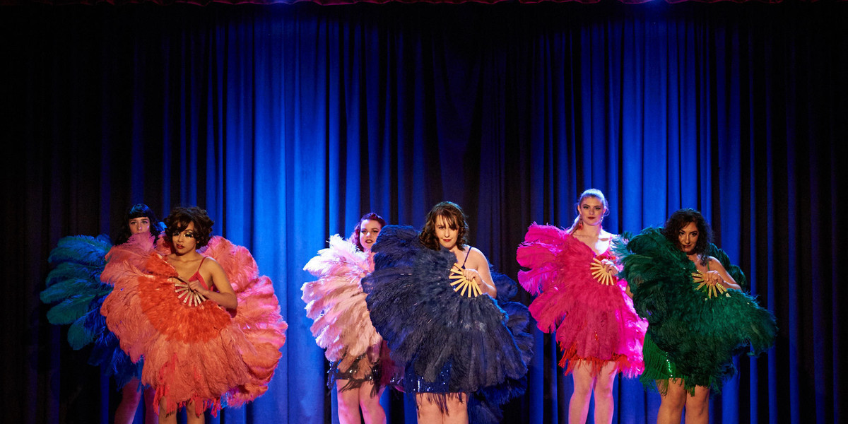 A troupe of fan dancers holding feather fans