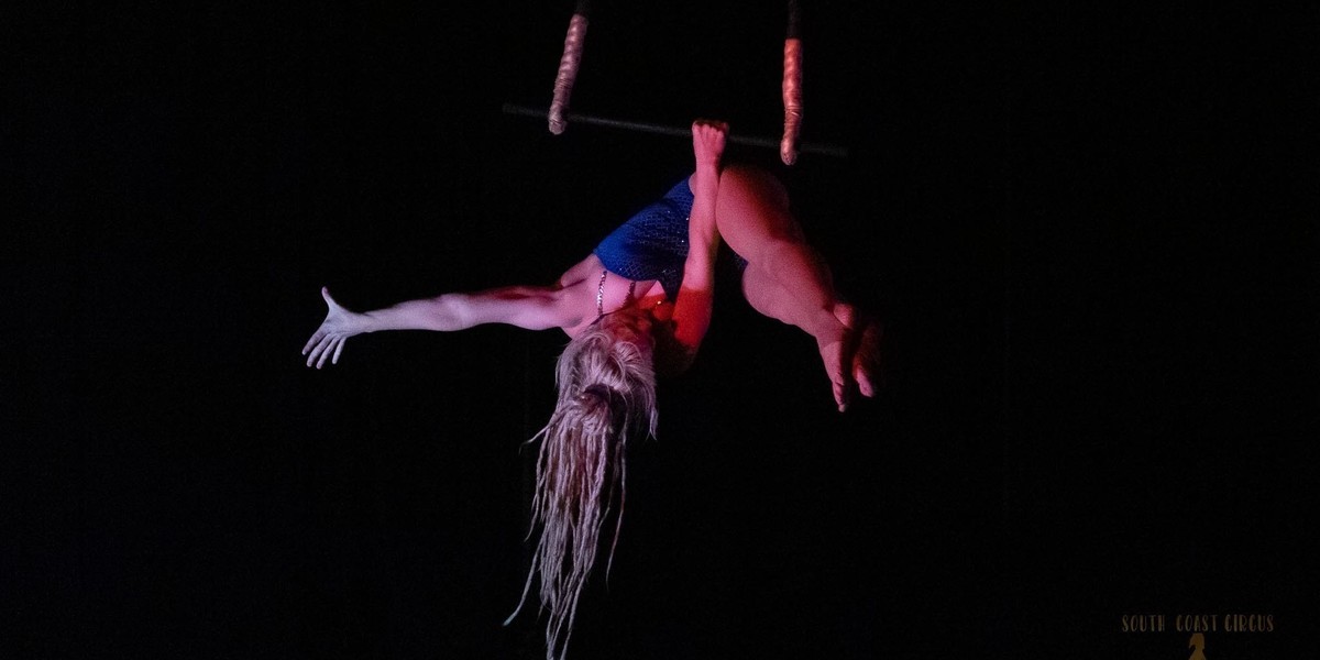 A woman poses in a strength move on the trapeze