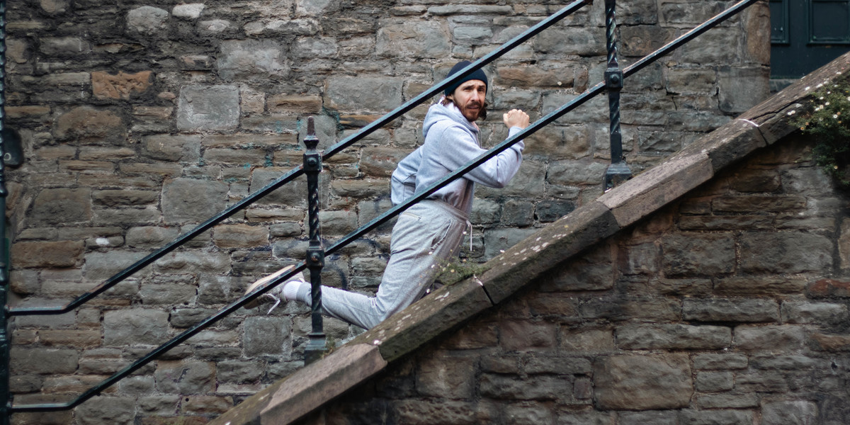 A man in a grey tracksuit runs up some staris