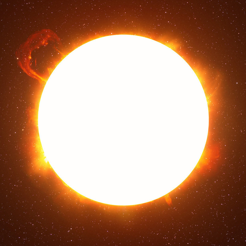 The sun, glowing a bright white, with orange solar flares extending from its circumference. The background is outer space- black with tiny freckled white stars.