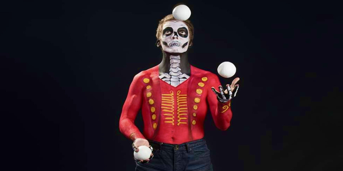 A person painted in circus tails juggles