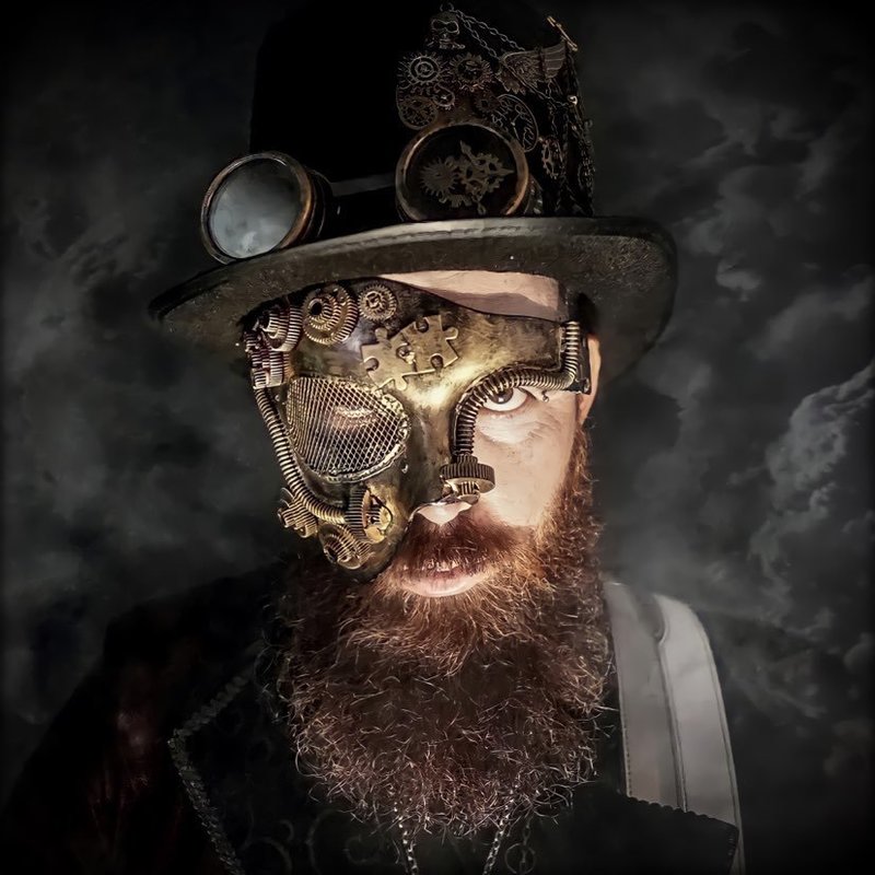 The Dark Lord, a bearded man with a steampunk hat and mask, stares intensly