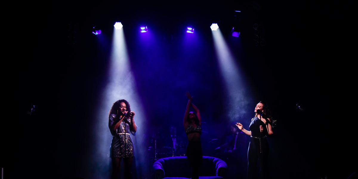 Paulini and Philippa Lynas singing on stage with Amelia Sanzo dancer in the background