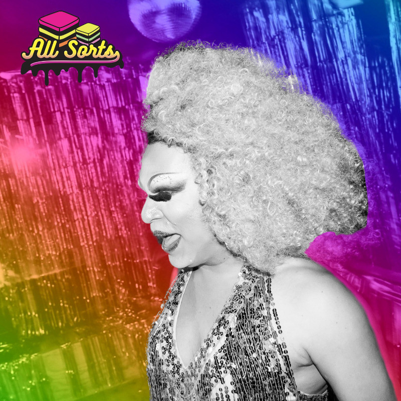 A black and white image of a drag queen with a blonde curly wig, large false eyelashes and a sequinned dress. She is side on facing the left looking down. The background is a rainbow filter over silver streamers and a disco ball, in the top left hand corner is a picture of two liquorice allsorts and the text "All Sorts" in yellow bubble font below.